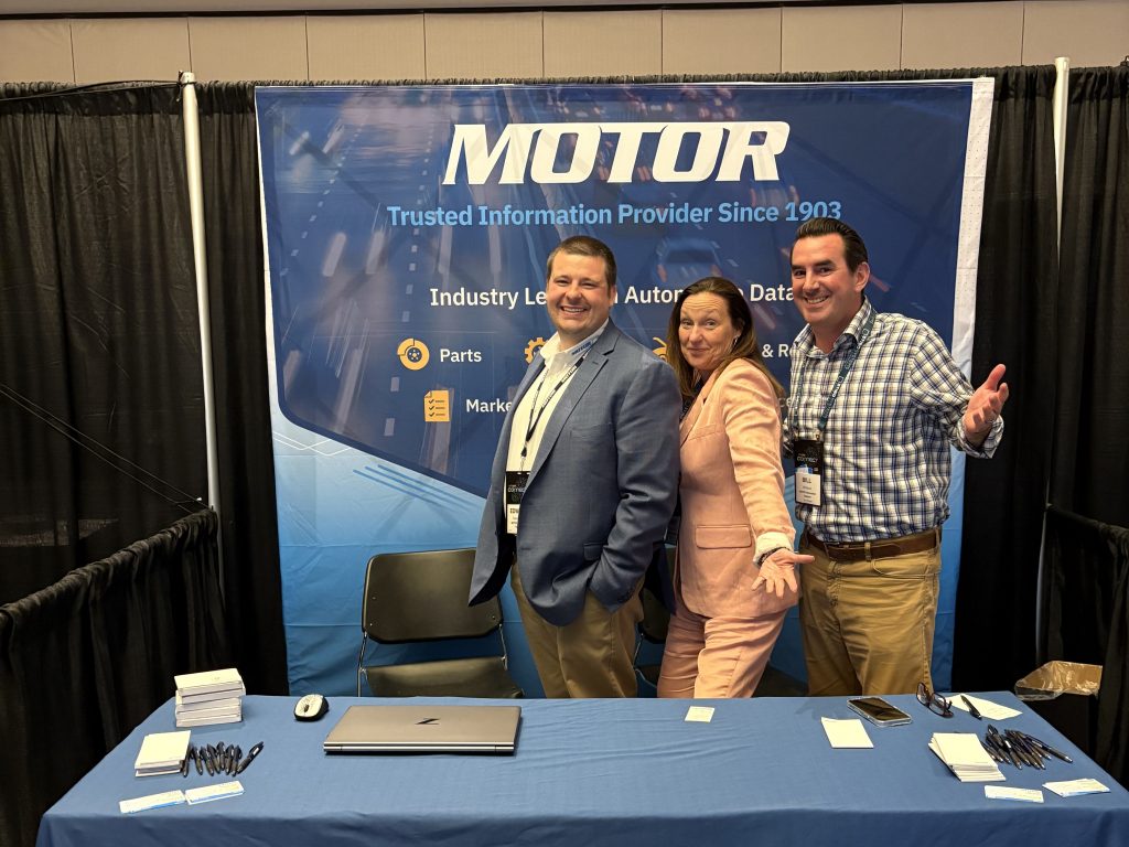 Three MOTOR team members posing at the Auto Care Connect 2025 event booth