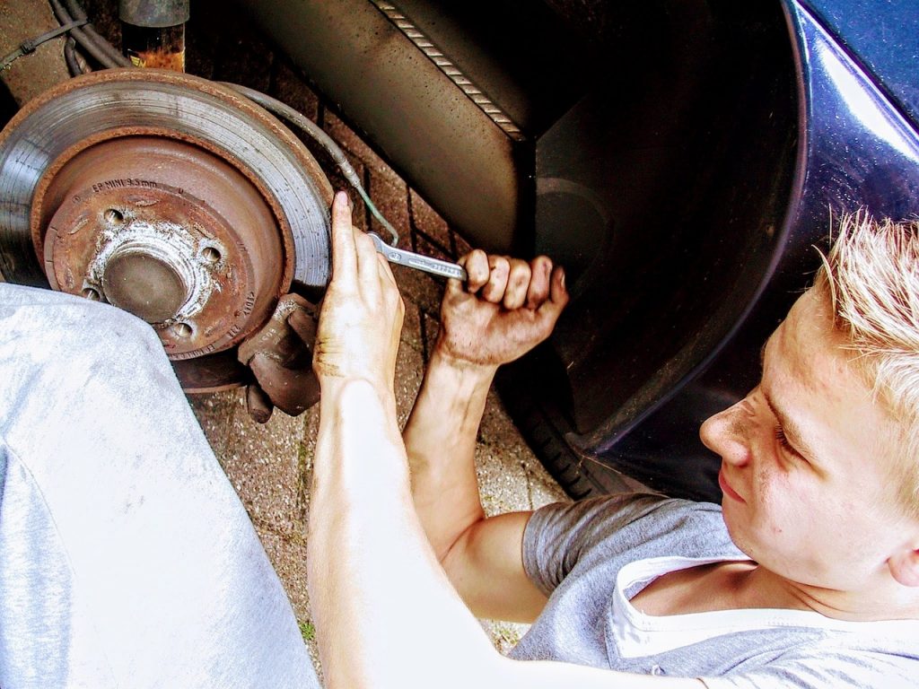 Young man using a tool to replace a vehicle's brake.